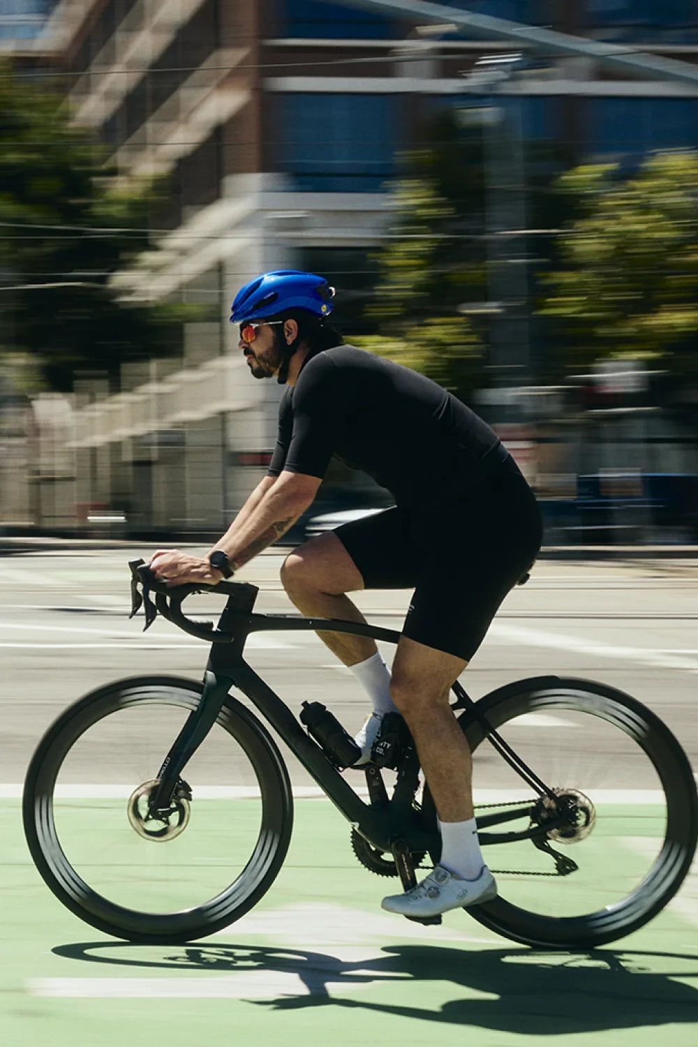 Rider on a road bike in a city bike lane wearing Lumos Aero GT in Gloss Blue
